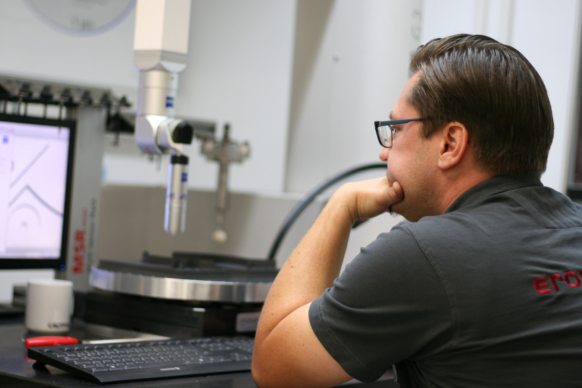 Ein Mitarbeiter Prüft an einer Carl Zeiss Contura G2 das Fertigungsergebnis der Fraesmaschinen von OPS Ingersoll
